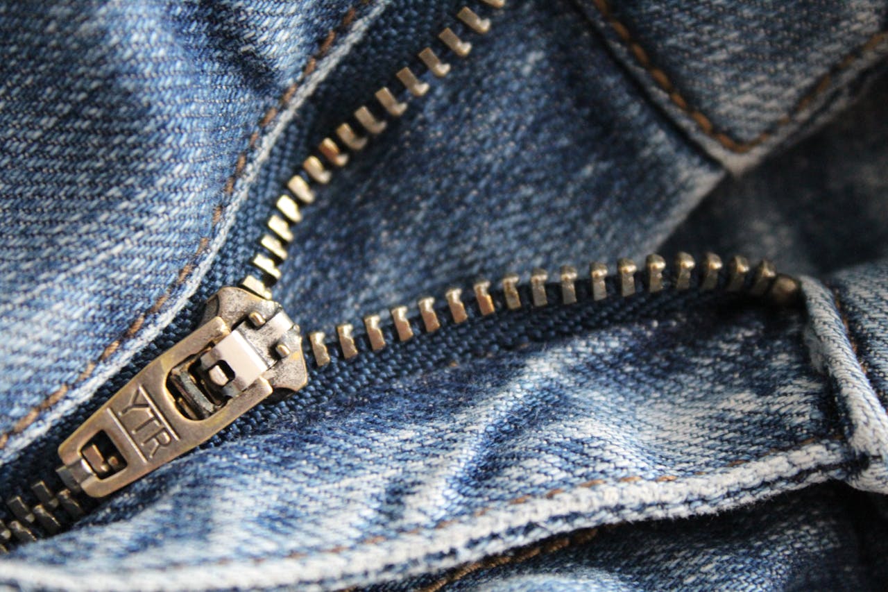 services-02 Detailed shot of a metal zipper on blue denim fabric, showcasing texture and craftsmanship.