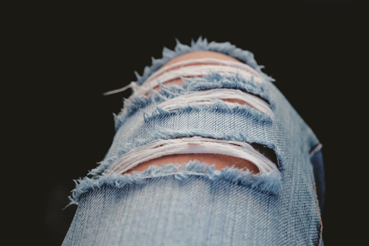 hero-img-01 Detailed shot of torn denim jeans showcasing modern fashion and style.